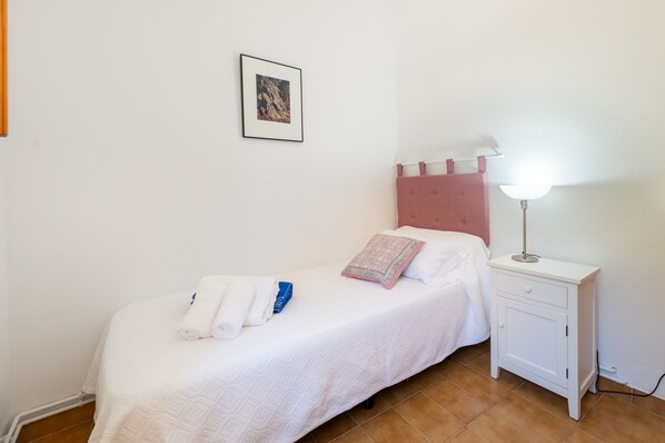 A single bed with a white bedspread, a pink headboard, and a bedside table with a lamp. - Villa "Can Joan den Coves" with Mountain View, Pool & Wi-Fi (Santa Gertrudis de Fruitera)