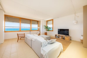 A living room with a large window, a sofa, a television, and a plant. - Villa Es Mollet with Sea View, Pool, Wi-Fi, Garden & Terrace (Son Serra de Marina)