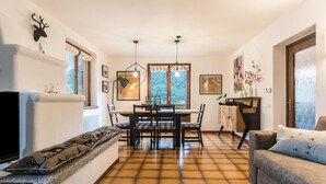 A living room with a fireplace, a dining area with a table and chairs, and a sofa.