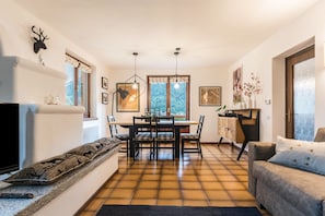 Un salon avec une cheminée, un coin repas avec une table et des chaises, et un canapé.