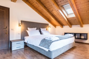 A bedroom with a wooden ceiling, a skylight, a bed with white bedding, a nightstand, and a wall-mounted shelf. - Apartment 'Casa Facco' with Mountain View, Private Garden and Wi-Fi (Bocenago)