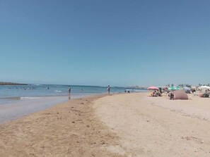 A beach with people walking and sitting under umbrellas. - La Grande Propriété Étoile De Mer (Skhirat)