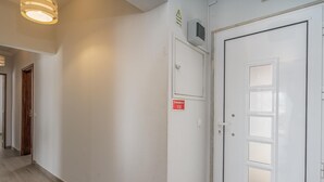 Ein Korridor mit einer weißen Tür, auf der „Emergencia 112“ steht, und einem Rauchmelder.