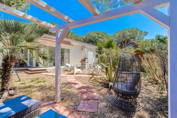 A covered outdoor area with a pergola, seating, and a decorative metal sculpture.