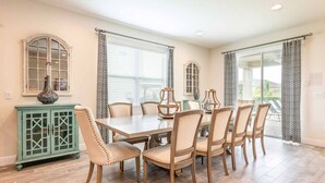 Une salle à manger avec une grande table, six chaises et un buffet vert.