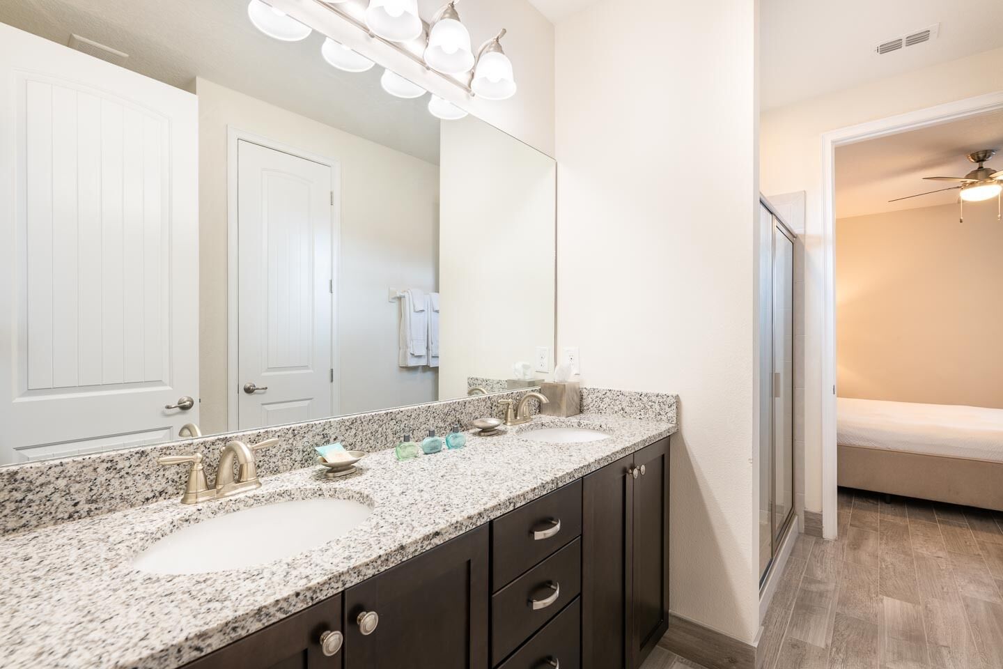 A bathroom with two sinks, a large mirror, and a ceiling fan.