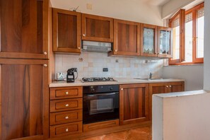 A kitchen with wooden cabinets, a gas stove, an oven, and a sink.
