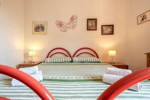 A hotel room with a bed, two bedside lamps, a wall with three framed pictures, and a decorative butterfly.