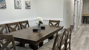 A dining area with a wooden table and chairs, white walls, and artwork on the wall. - GOTL Strip Suite #3- Sunset Vacation Rentals (Geneva)