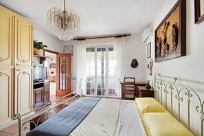 Un dormitorio con cama, televisor, escritorio y silla.
