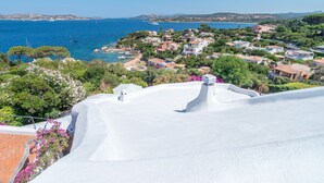 A coastal village with white buildings, a clear blue sea, and lush greenery.