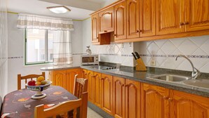 A kitchen with wooden cabinets, a microwave, a sink, and a fruit bowl on the table.