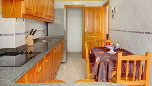 A kitchen with wooden cabinets, a stove, and a dining table with chairs.