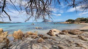 A rocky beach with clear water and a mountainous backdrop. - Villa LUNA ROSSA with Sea View, Pool, A/C, Wi-Fi, Garden, Terrace & Balcony (san teodoro)