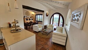A spacious living area with a dining table, two white sofas, a coffee table, and a kitchen area with a sink and countertop. - Villa LUNA ROSSA with Sea View, Pool, A/C, Wi-Fi, Garden, Terrace & Balcony (san teodoro)