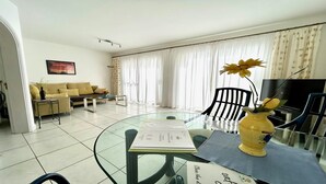 Una sala de estar moderna con una mesa de centro de vidrio, un sofá y un televisor.