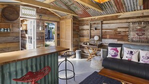 Interior d'una cabana rústica amb una barra de fusta, cadires vermelles, un sofà de cuir negre i una zona de menjador.