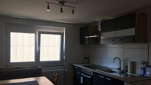 Una cocina con una mesa de comedor, armarios, estufa y lavavajillas.