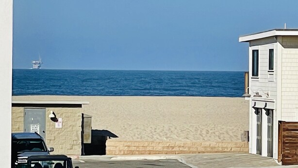A beachside building with a view of the ocean and a distant ship. - The Deck House on the Silver Strand (Oxnard)