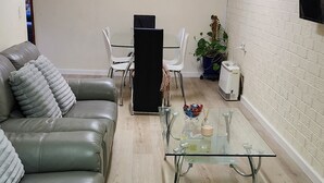 A living room with a green leather sofa, a glass coffee table, and a painting on the wall. - Cooma home with fresh air and a mountain view (Cooma)