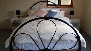 A bed with a metal frame, white bedding, and two bedside tables with lamps. - Cooma home with fresh air and a mountain view (Cooma)