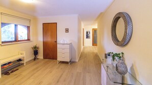 A hallway with a wooden floor, a white bench, a white dresser, a mirror, and a glass shelf with a vase. - Cooma home with fresh air and a mountain view (Cooma)