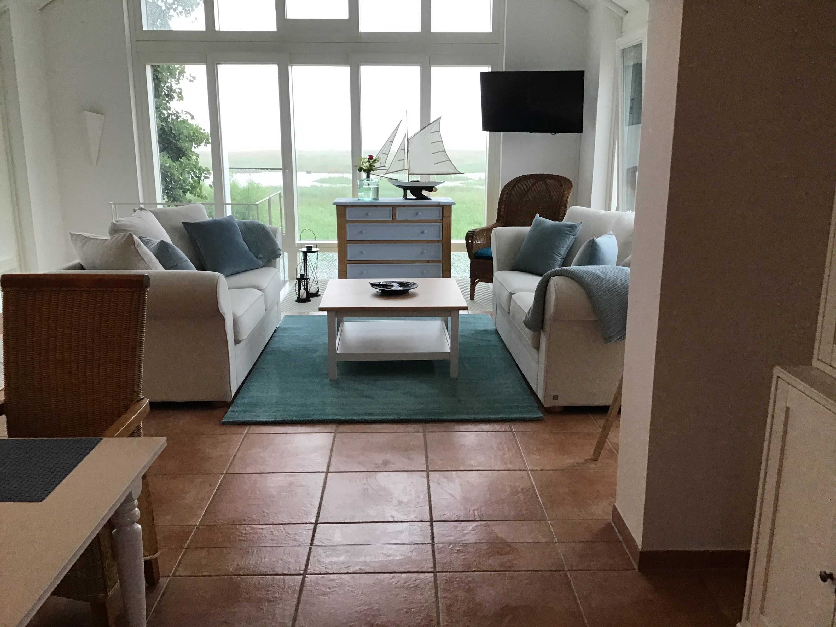 Un salon avec deux canapés, une table basse, un téléviseur et une vue sur l’extérieur.
