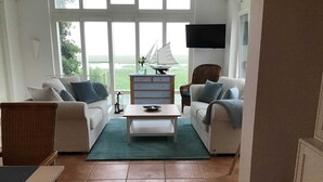 Un salón con dos sofás, una mesa de centro, un televisor y vistas al exterior.