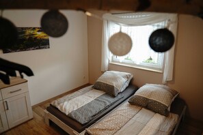 En enkeltseng med mønstret sengetøj, et sengebord og et vindue med gardiner.