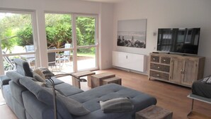 Ein modernes Wohnzimmer mit einem grauen Sofa, einem Fernseher und einer Holzkabine.