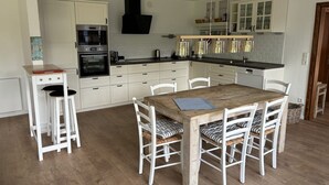 Eine Küche mit weißen Schränken, einem Holztisch und einem eingebauten Backofen.