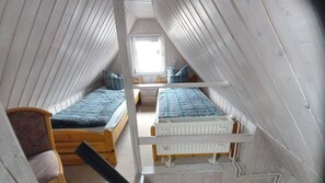 Une chambre de dortoir avec deux lits superposés en bois, un petit bureau et une fenêtre.
