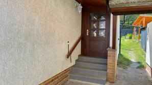 Una entrada de casa con una escalera de madera que conduce a una puerta con paneles de vidrio.