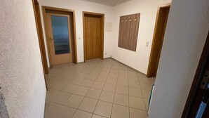 Un pasillo con piso de baldosas, puertas de madera y una lámpara en el techo.