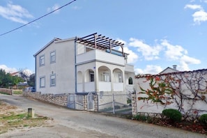 A two-story house with a balcony, stone wall, and a gate. - Apartment in Maslenica with Sea View (Maslenica)