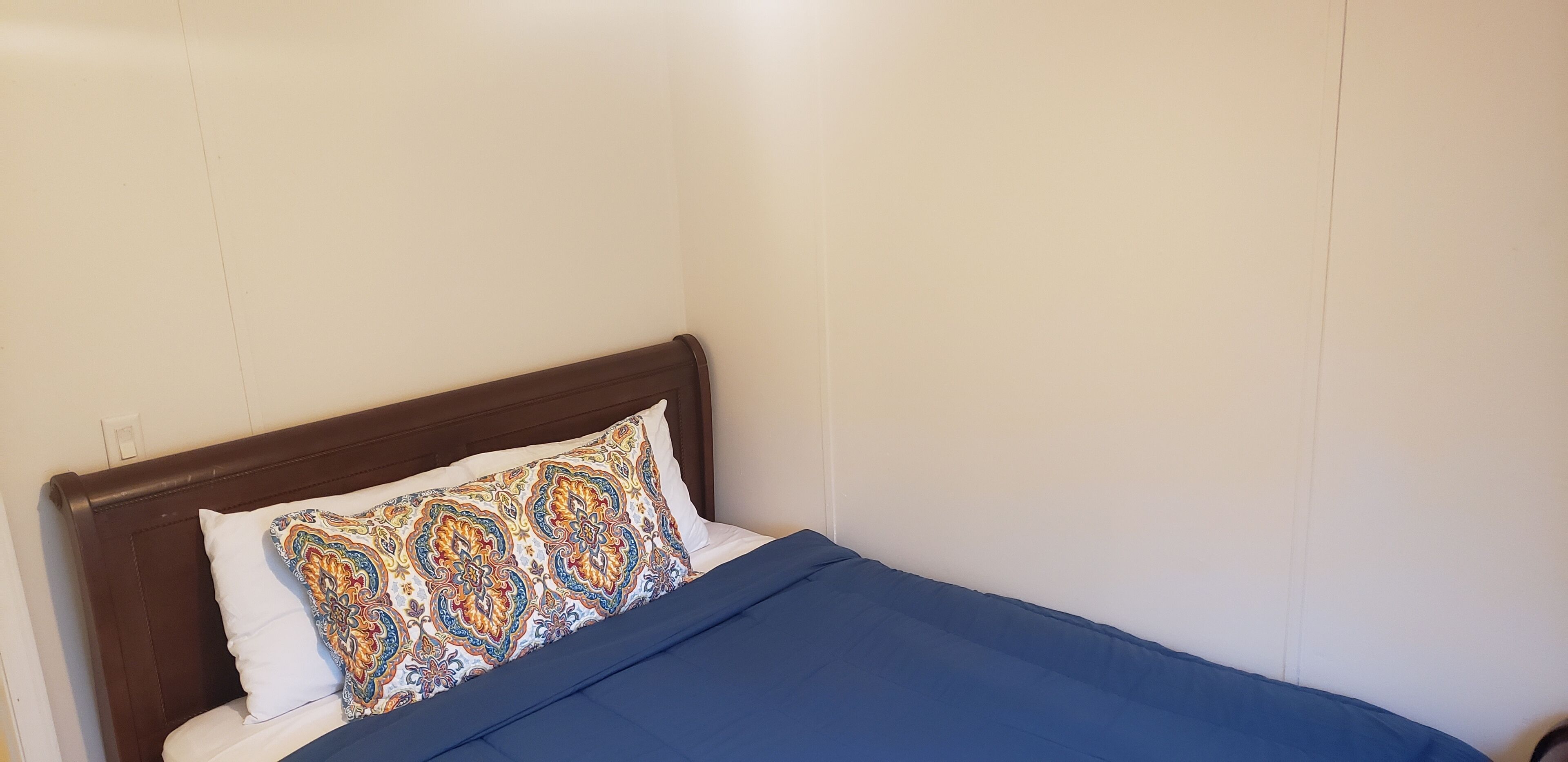 A bed with a patterned pillow and a blue blanket.