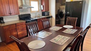 A dining area with a wooden table set for four, surrounded by wooden chairs. - THE LIONS DEN  Home Next to  Lion & Tiger Reserve (Burlington)
