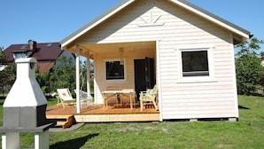 A small, single-story wooden cabin with a porch, a table, and two chairs. - Bungalow in Kolczewo near Baltic Sea (Kolczewo)