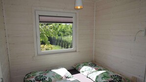 Una stanza piccola con un letto, una finestra con persiane e un lampadario.