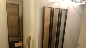 Un couloir avec une porte en bois, un miroir et trois miroirs verticaux accrochés au mur.