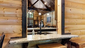 Ein Holzblockhaus-Interieur mit einer Granit-Arbeitsplatte, einem Waschbecken und einer Bank.