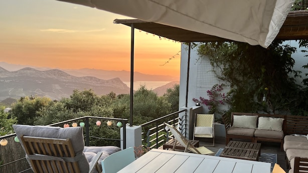 Eine Terrasse im Freien mit Tisch, Stühlen und einer Sitzecke, mit Blick auf Berge.