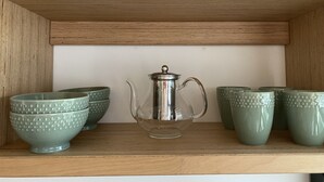 A shelf with a metal teapot and six green cups. - L'Oasis de Saint-Jacques (SAINT DENIS)