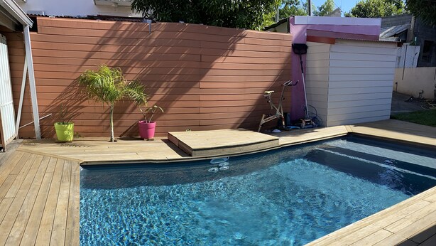 A rectangular swimming pool with clear blue water, surrounded by a wooden deck. - L'Oasis de Saint-Jacques (SAINT DENIS)