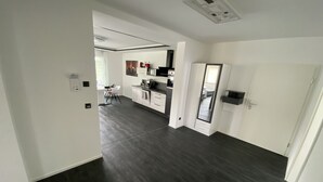 A modern kitchen with dark flooring, white cabinetry, and a built-in oven. - Apartments -Saaldorf WG 5 with balcony and view of the reservoir (Bad Lobenstein)