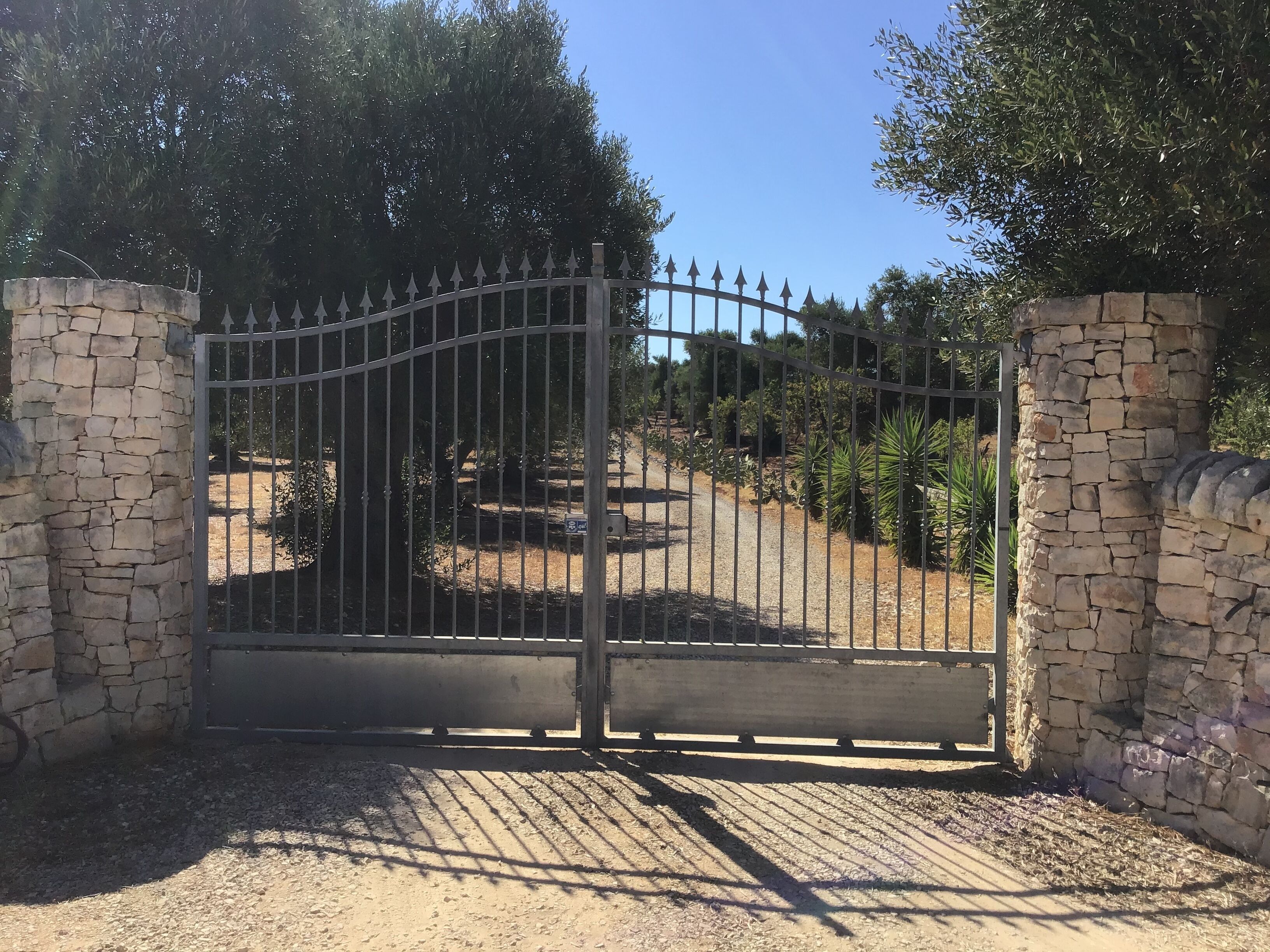 A gated entrance with stone walls and a metal gate.