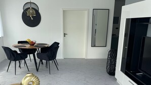 Un espace de vie moderne comprenant un coin repas, un grand miroir et un téléviseur.