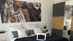 Une chambre moderne avec un grand lit, une table de chevet, un miroir et un téléviseur fixé au mur.