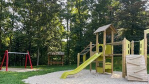 Une aire de jeux avec un toboggan, des structures d’escalade et une balançoire.