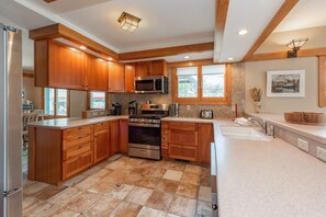 A modern kitchen with wooden cabinets, stainless steel appliances, and a large island.